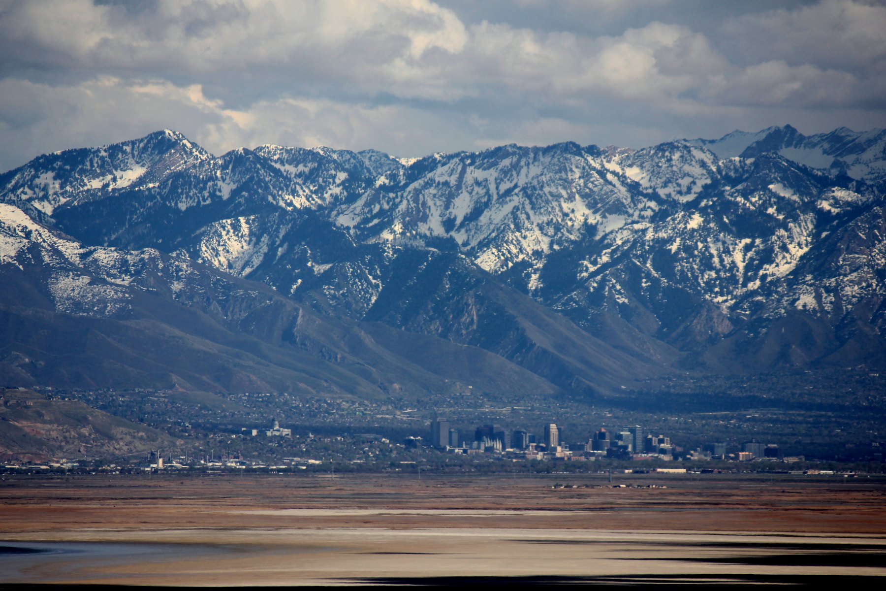 Salt Lake City skyline below the snow-covered Wasatch Range, with the lakebed in the foreground